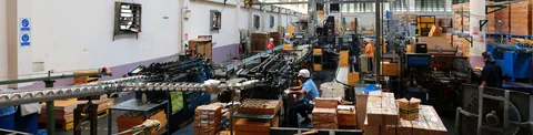 Interior d'una planta industrial amb maquinària i operaris treballant