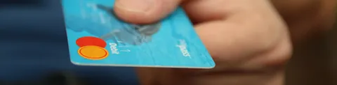 Mano que sostiene una tarjeta de pago azul